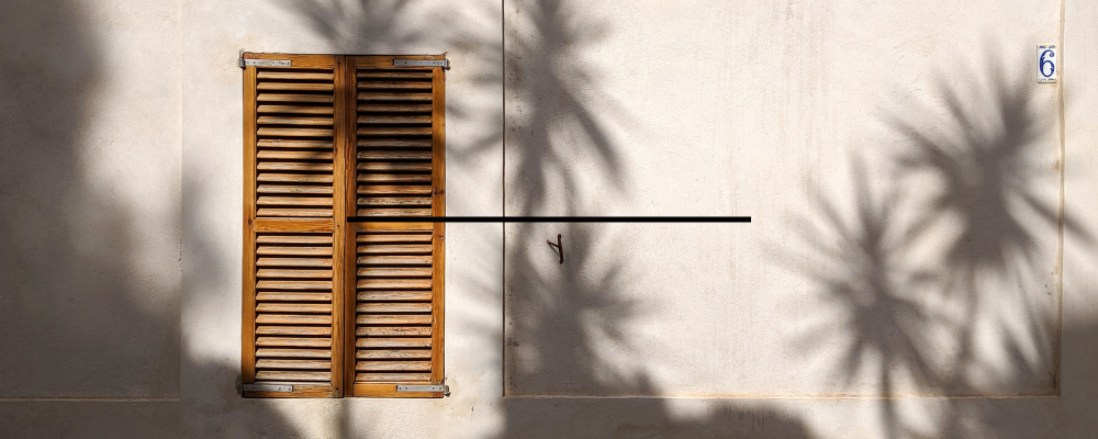 fenêtre d'une maison méditéranéenne avec soleil et palmier