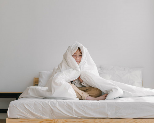 Enfant assis sur un lit couvert par un drap housse