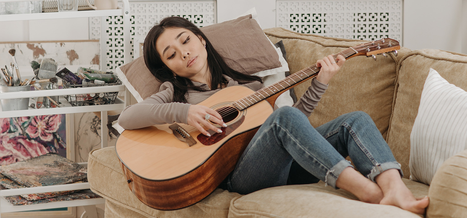 Femme jouant de la guitare sur un canapé