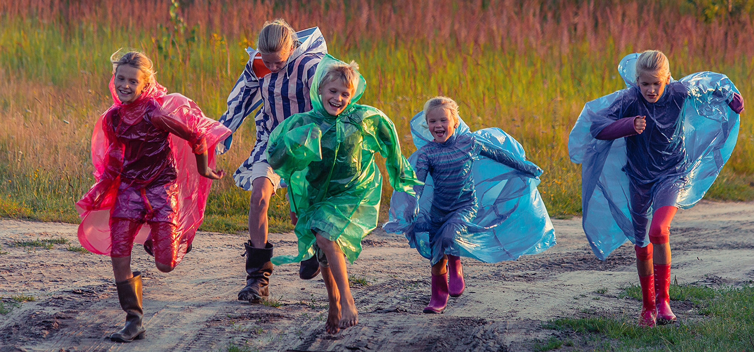 Enfants qui courent dehors avec des imperméables colorés
