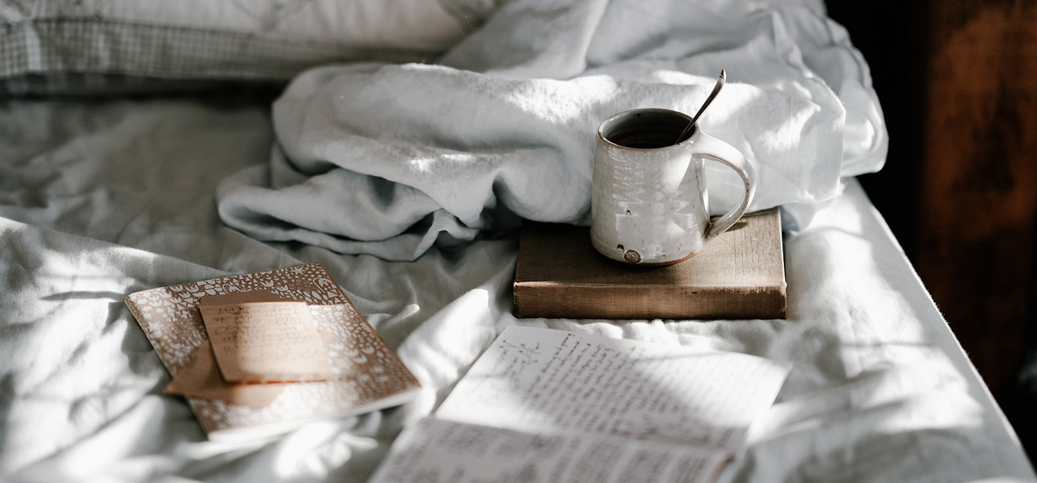 Tasse de café et livre posés sur un lit