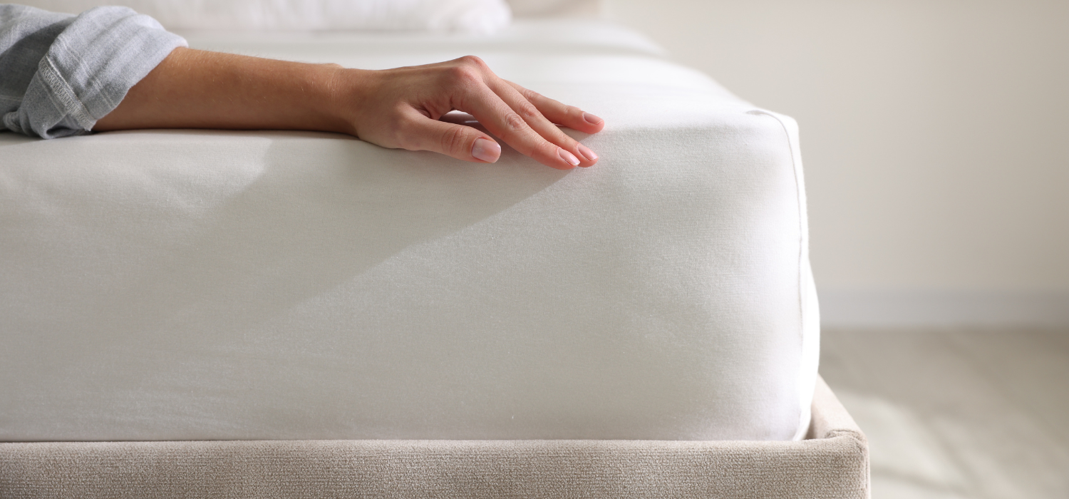 Main pos&eacute;e sur un matelas ferme illustrant le soutien et la qualit&eacute; du couchage pour les personnes souffrant de mal de dos.