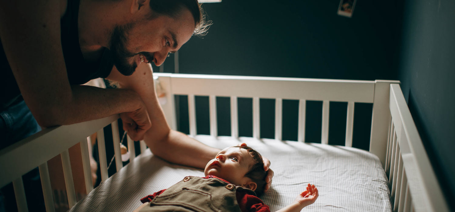 Parent aupr&egrave;s de son b&eacute;b&eacute; install&eacute; dans son lit &agrave; barreaux